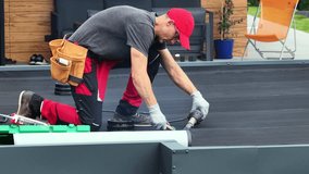 A skilled worker applies heat to EPDM roofing material while installing a new roof in a backyard. The surrounding area features modern outdoor furniture and greenery. - Powered by Shutterstock - Get 15% off with code: PIKWIZARD15