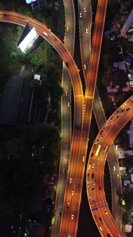 Aerial top view of overpass and city traffic at night. Vertical video 4k