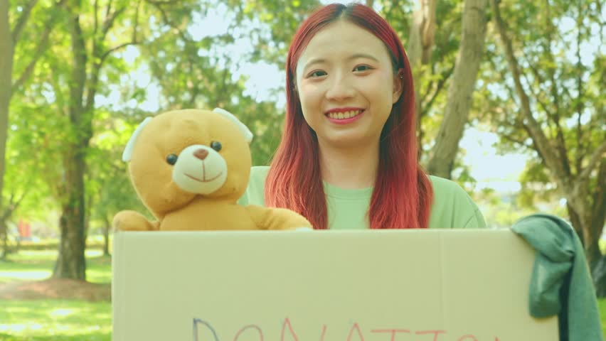 Female volunteer representing the foundation holds donation box for toys and used clothes join charity event to pass on to the poor with a smile : Female volunteers are happy work for society.
