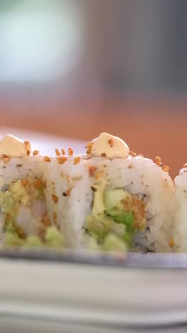 Chef cooking making sushi, pouring sauce falling sprinkles with sesame seeds. Fresh Sushi . Japanese sushi roll macro close up view, blurred background 