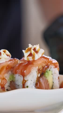 Chef cooking making sushi, pouring sauce falling sprinkles with sesame seeds. Fresh Sushi . Japanese sushi roll macro close up view, blurred background 