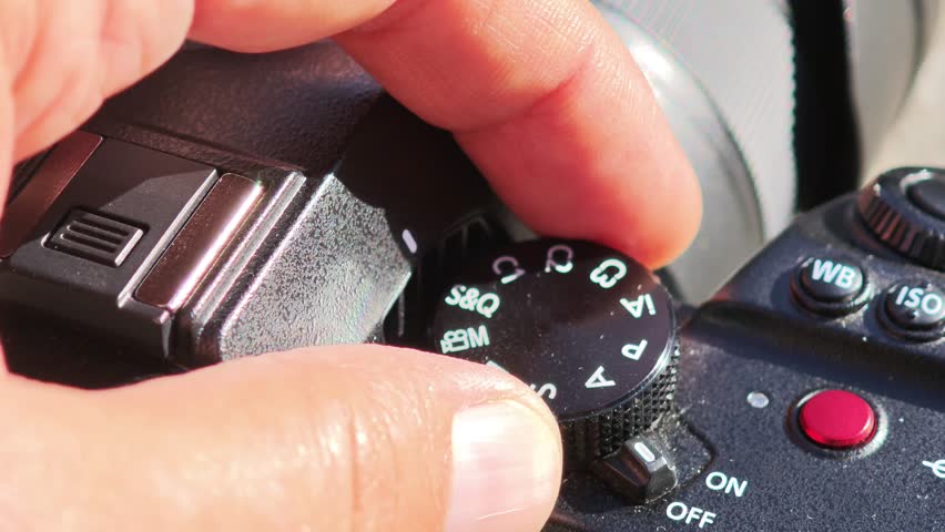 Hand turning mode dial on professional digital camera