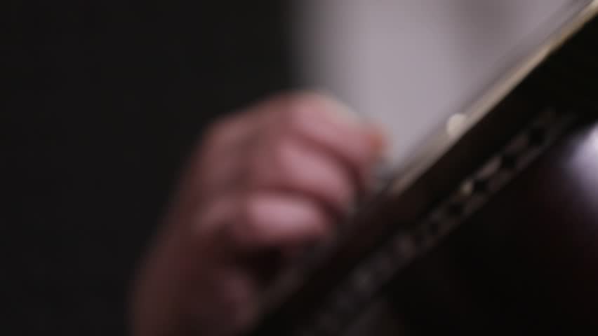 Close-up of a musician's hands playing the Tar, a traditional Persian string instrument. Shallow depth of field focuses on the fretwork during an intimate cultural music performance