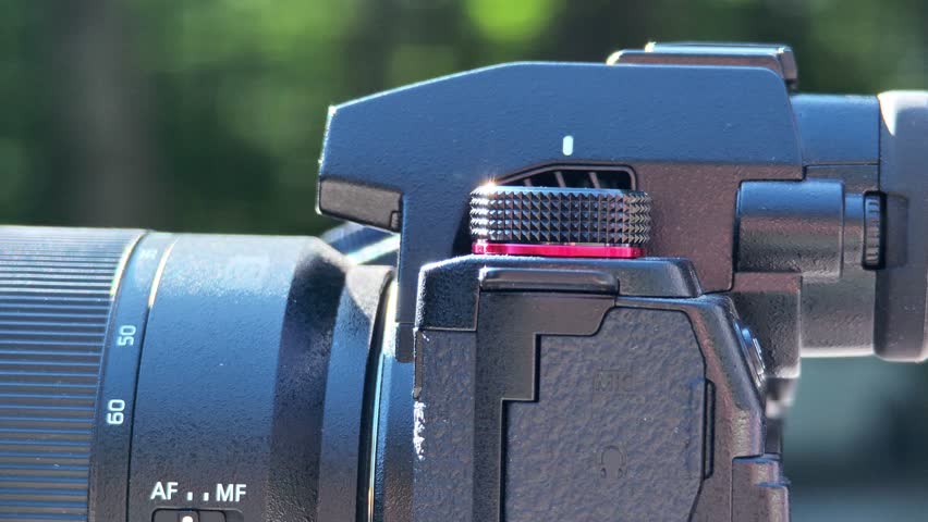 Professional videographer carefully adjusting camera settings, focusing lens with precise hand movements, manipulating technical controls for optimal image quality and recording setup