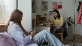 Shot of two girls as roommates chatting in dorm room studying and showing something on smartphone screen - Powered by Shutterstock - Get 15% off with code: PIKWIZARD15