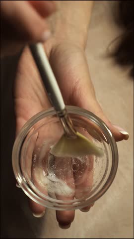 Beautician mixes cleansing exfoliating peeling gel for face skin in a bowl, close-up, top view, vertical. Rejuvenating beauty procedure in the beauty parlor.