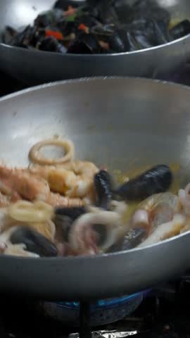Chef cooking flambe shrimps with oil on wok frying pan close-up. Shrimp, octopus on fire throwing them in pan. Restaurant Food concept. Sea food. Slow motion 