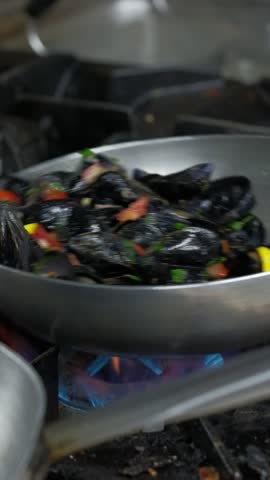 Preparation of mussels. Chef is cooking mussels with white wine at a kitchen of a restaurant. Slow motion. Close up. High quality FullHD footage