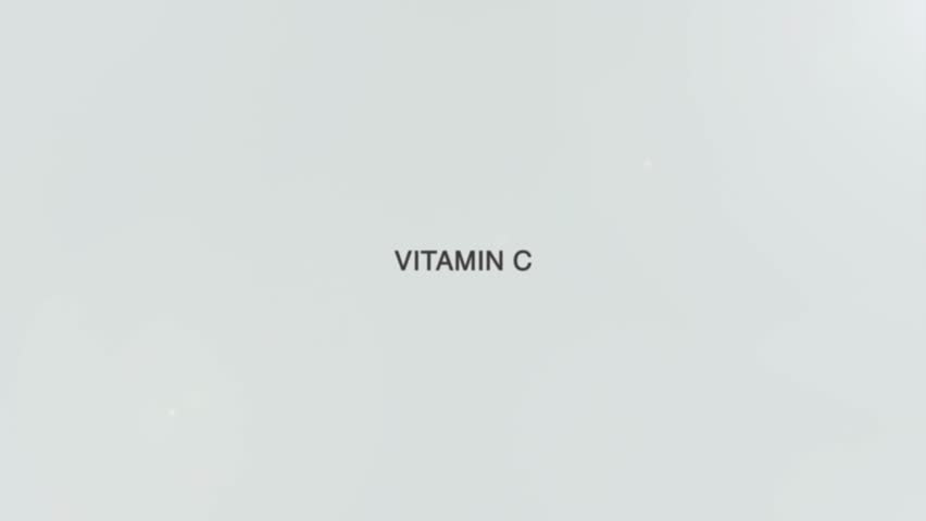 A hand holds a magnifying glass over the words "Vitamin C" on a white background. The lens enlarges the phrase, symbolizing focus on immunity, antioxidant power, skin health, and the essential role