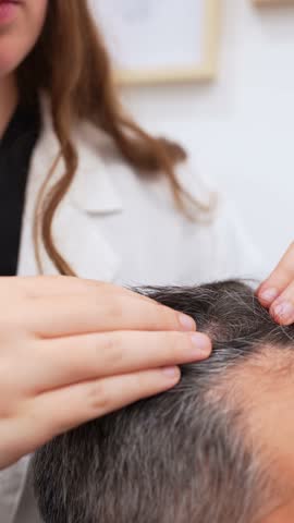 Doctor examining a male patient's hair and scalp, preparing for a hair transplant procedure, captured in slow motion