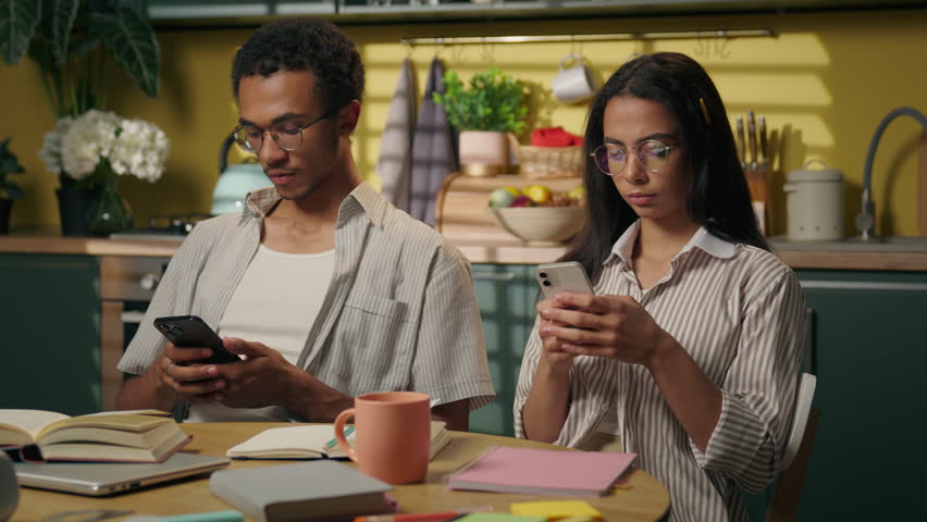 Multiracial teens high school students guy girl African American man Arabian woman ignoring browsing smartphones online shopping at home kitchen social media addict using gadgets playing mobile phones