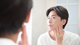 A Japanese man checking his appearance in the morning in front of the mirror above the sink. Beard removal and shaving. Video. - Powered by Shutterstock - Get 15% off with code: PIKWIZARD15