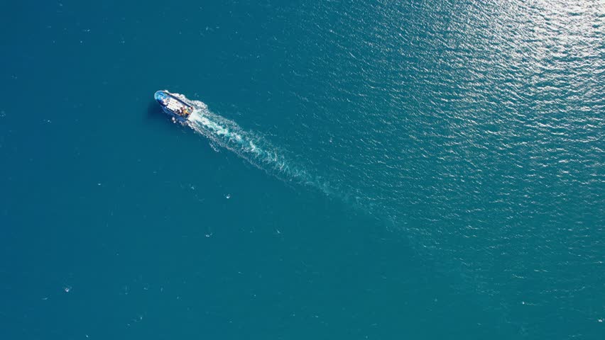 Inland cargo ship in blue sea water or river, aerial top view. Service auxiliary boat for fishing nets and fish farms trout cages.