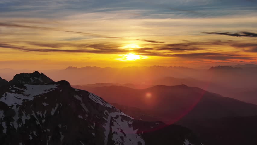 Aerial view of amazing rocky mountains in snow and sunset sun, 4k