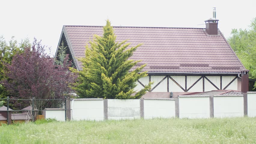 Half-timbered house behind a fence among trees