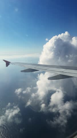 View from an airplane, a passenger plane flies over the sea at dawn. Airplane wing in the clouds. 