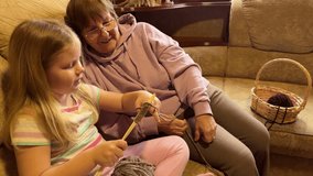 A loving grandmother teaches her granddaughter to knit with fluffy yarn in a warm, inviting living room setting. - Powered by Shutterstock - Get 15% off with code: PIKWIZARD15