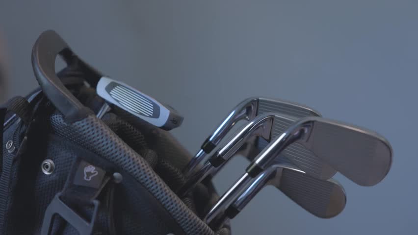 static shot of modern golf irons and putter sitting on a stand bag