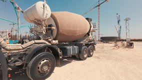 Handheld real-time footage of concrete mixer truck at construction site. Tower cranes at background. Concrete work in progress. Infrastructure, construction, urban development, industrial machinery - Powered by Shutterstock - Get 15% off with code: PIKWIZARD15