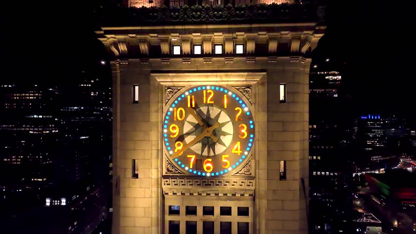 Aerial shot of Boston’s historic Custom House Clock Tower at dusk. City lights glow as the skyline blends old architecture with modern urban energy in this cinematic flyover.