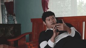 businessman lying on wooden chair in room wearing black and white t-shirt and working or trading stocks on phone - Powered by Shutterstock - Get 15% off with code: PIKWIZARD15