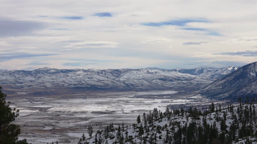 Eastern Sierra Nevada mountains partially covered in snow with pine trees spreading at its base 