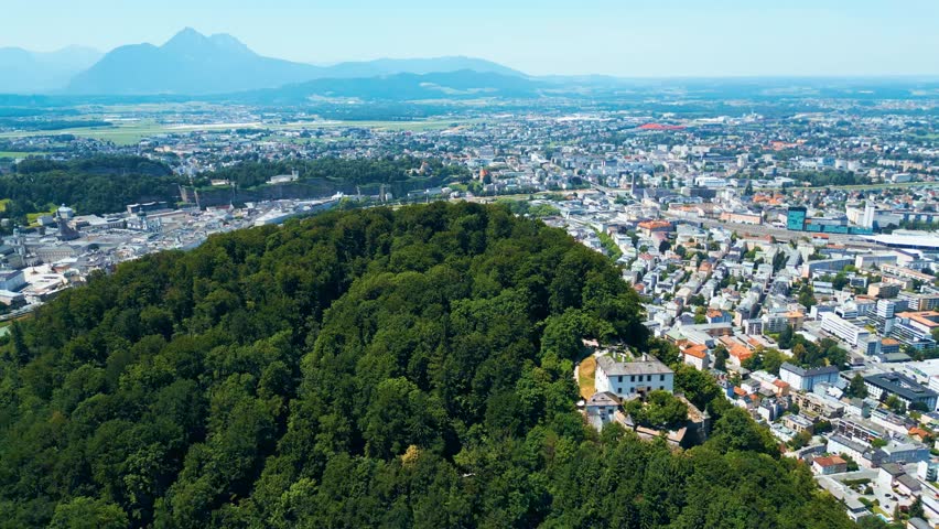Salzburg, Austria, aerial view of the historic old town with Hohensalzburg Fortress, Salzach River, baroque architecture and surrounding Alps. Captured on a sunny summer day from a drone