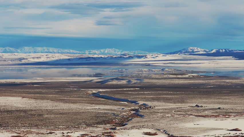 Eastern Sierra Nevada mountain range in the distance partially covered in snow and in the foreground Mono Lake basin 