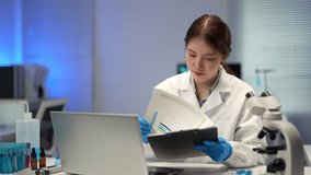 Laboratory technician analyzing data on a clipboard and working on a laptop, with microscope and test tubes nearby, performing scientific research - Powered by Shutterstock - Get 15% off with code: PIKWIZARD15