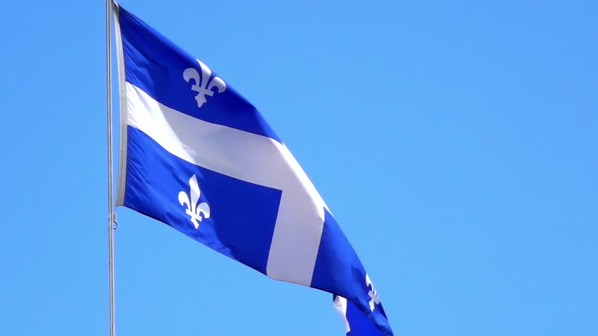 The blue and white flag of Quebec, featuring fleur-de-lis, proudly waves against a clear sky, symbolizing provincial identity.