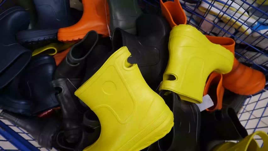 Many multi-colored rubber boots lying in a box. New rubber boots for hunting and fishing, summer cottages, farming. Special industrial footwear.