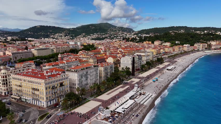  Aerial drone flying forward over Nice Promenade in France, colorful city buildings and blue Mediterranean beach coastline in Nice.
