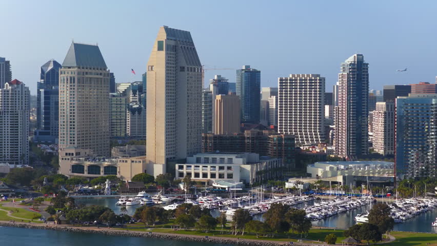 Aerial footage highlights Downtown San Diegos skyline, modern architecture, green parks, and a bustling marina with boats sailing on shimmering water, capturing the citys vibrant atmosphere