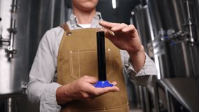 Brewer analyzing fresh dark beer sample for quality control in stainless steel tanks. - Powered by Shutterstock - Get 15% off with code: PIKWIZARD15