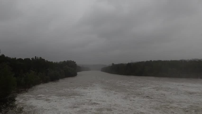 Wide river is flooding after rainfall and the flood gates are open.