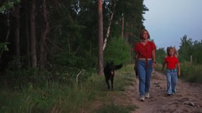 Mother and daughter enjoy a walk with their dog through a summer forest filmed in slow motion. Adorable scene of Caucasian family spending time together on nature and caring in the countryside. - Powered by Shutterstock - Get 15% off with code: PIKWIZARD15