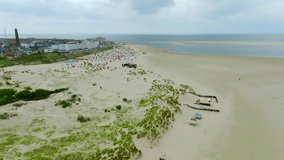 Wide sandy beach lined with colorful strandkorbe in front of Borkum town and sea. Aerial orbit view - Powered by Shutterstock - Get 15% off with code: PIKWIZARD15