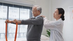  Asian female doctor or physiotherapist guides her elderly male patient through shoulder muscle exercises using a medical resistance band. She carefully monitors posture and offers hands-on support  - Powered by Shutterstock - Get 15% off with code: PIKWIZARD15