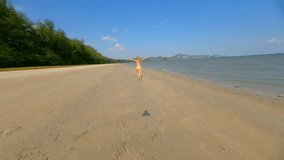 FPV drone shot of blonde woman in yellow bikini joyfully skipping along tropical beach in Thailand. Sunny, active, and playful summer scene. Perfect for lifestyle, travel, and freedom concepts. - Powered by Shutterstock - Get 15% off with code: PIKWIZARD15