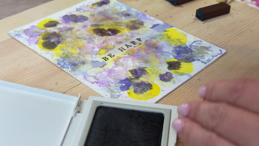 Floral print card with stamped text "Be Happy" – handmade botanical art with flower pigments, ink pad, wooden letters, and natural decor, top view