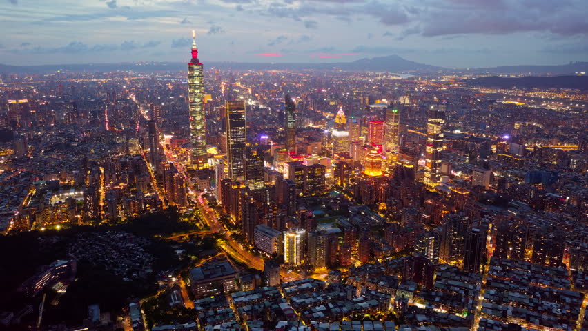 Aerial hyperlapse of Downtown Taipei at night, the vibrant capital city of Taiwan, with 101 Tower standing out amid skyscrapers in XinYi Commercial District and city lights dazzling under in the dark
