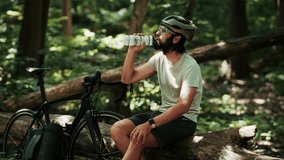 Cyclist drinks water from bottle after intense MTB training. Athletic man hydrates during triathlon cycling. Sporty lifestyle, endurance recovery in outdoor mountain biking. Cyclist isotonic drinks - Powered by Shutterstock - Get 15% off with code: PIKWIZARD15