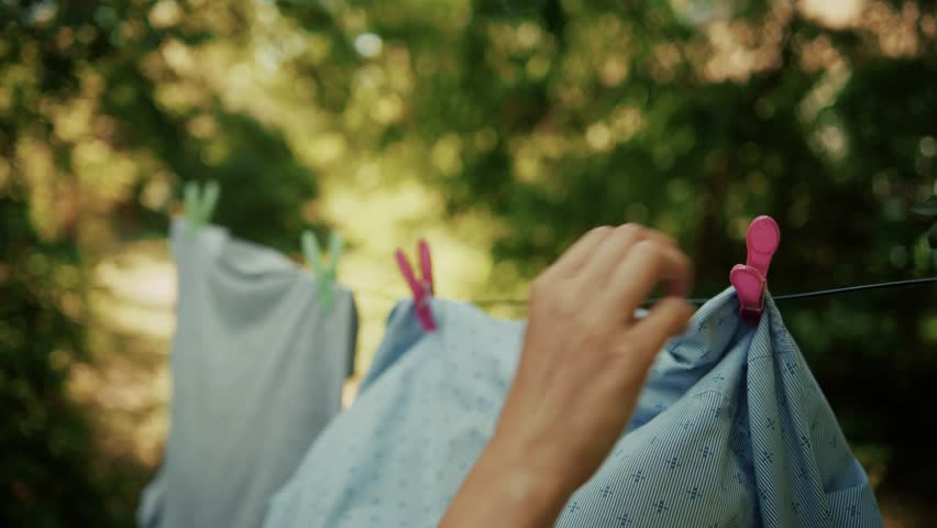 hang freshly washed clothes on clothesline. Freshly washed clothes flutter gently on backyard clothesline, drying under open sky. Colorful garments secured pins sway in breeze simple domestic laundry