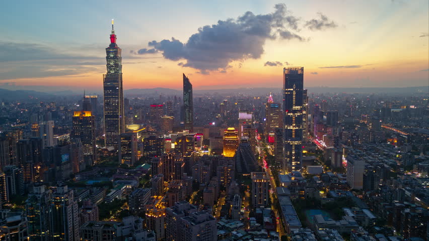 Aerial hyperlapse of Downtown Taipei at dusk, the vibrant capital city of Taiwan, with 101 Tower standing out amid skyscrapers in XinYi Commercial District and city lights dazzling under twilight sky