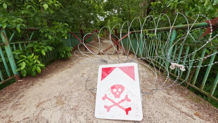 Barricaded area with barbed wire and a visible warning sign. Heavily guarded border fence symbolizing imprisonment, illegal immigration control, restricted access, and high-security prison zone