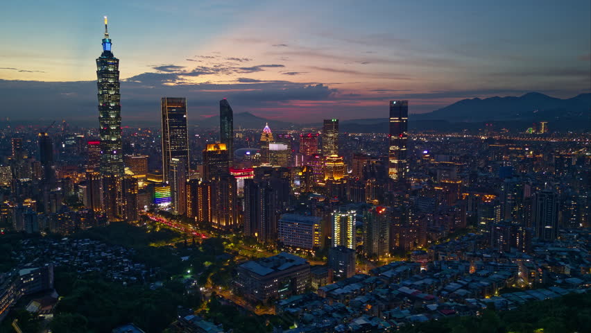 Aerial hyperlapse of Downtown Taipei at nightfall, the vibrant capital city of Taiwan, with 101 Tower standing out amid skyscrapers in XinYi Commercial District and city lights dazzling in the dark