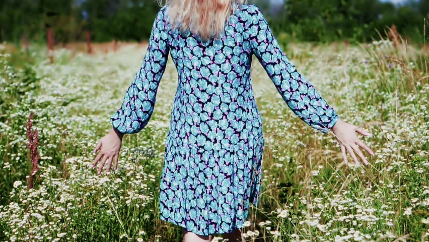 chamomile flowers field. woman walks through summer meadow, gently touching tall grass and wildflowers. Enjoys peaceful vacation morning, embracing nature, freedom and calm outdoor adventure meadow