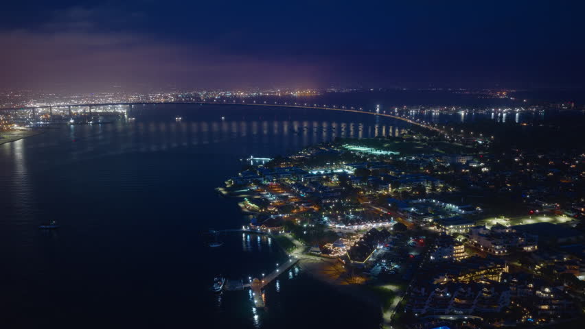 Enjoy a stunning aerial view of Downtown San Diego at night, which beautifully showcases the vibrant city lights, peaceful waterfront, and the famous, iconic bridge that defines the landscape