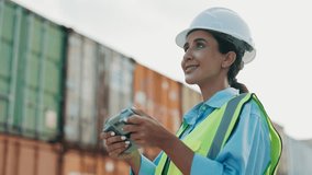 Woman Supervisor Handles Drone Remotely, Wearing Safety Equipment, While Overseeing Warehouse. Female Employee Conducts Aerial Inspections With Drone Outdoors. Container Import And Logistics Concept - Powered by Shutterstock - Get 15% off with code: PIKWIZARD15