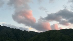 Fast-moving clouds cross the sky over a green mountain ridge during dusk. The pastel colors add a peaceful atmosphere. - Powered by Shutterstock - Get 15% off with code: PIKWIZARD15
